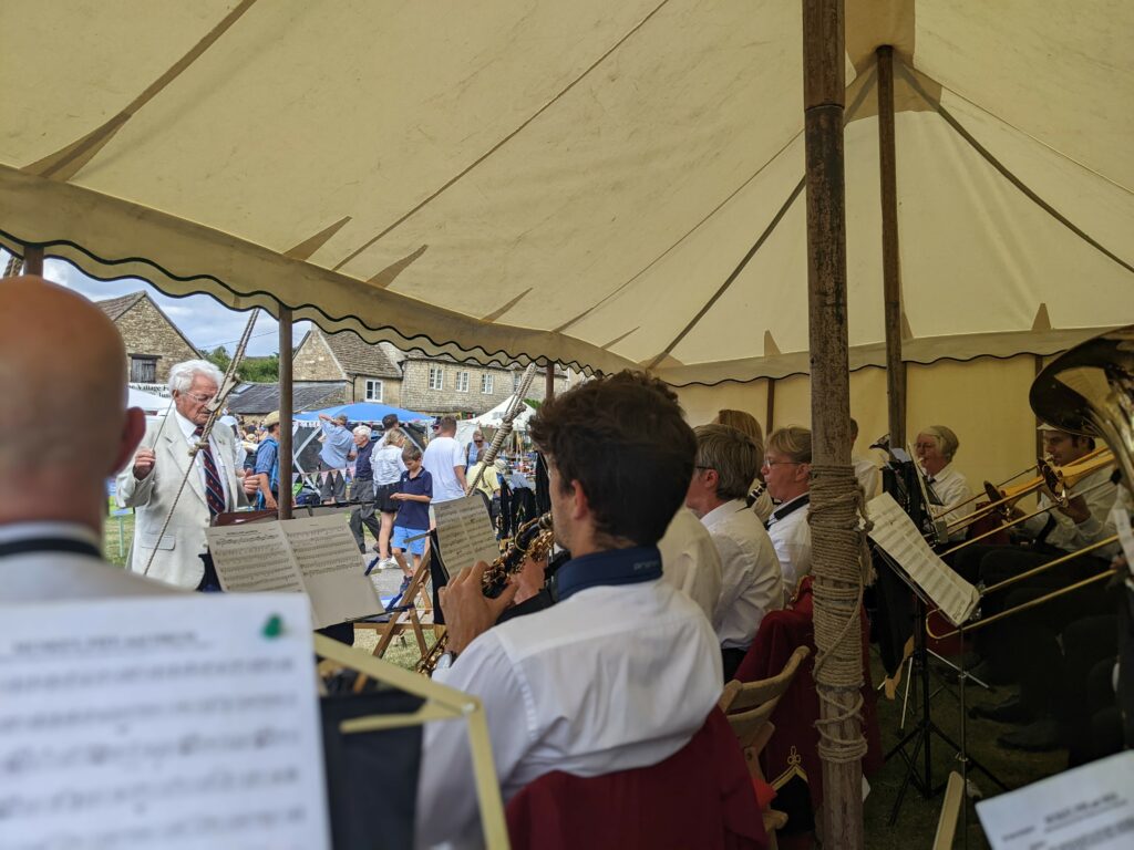 View from inside the band tent at Biddestone Village Fete of the conductor, soprano saxophones, clarinets, horn and trombones